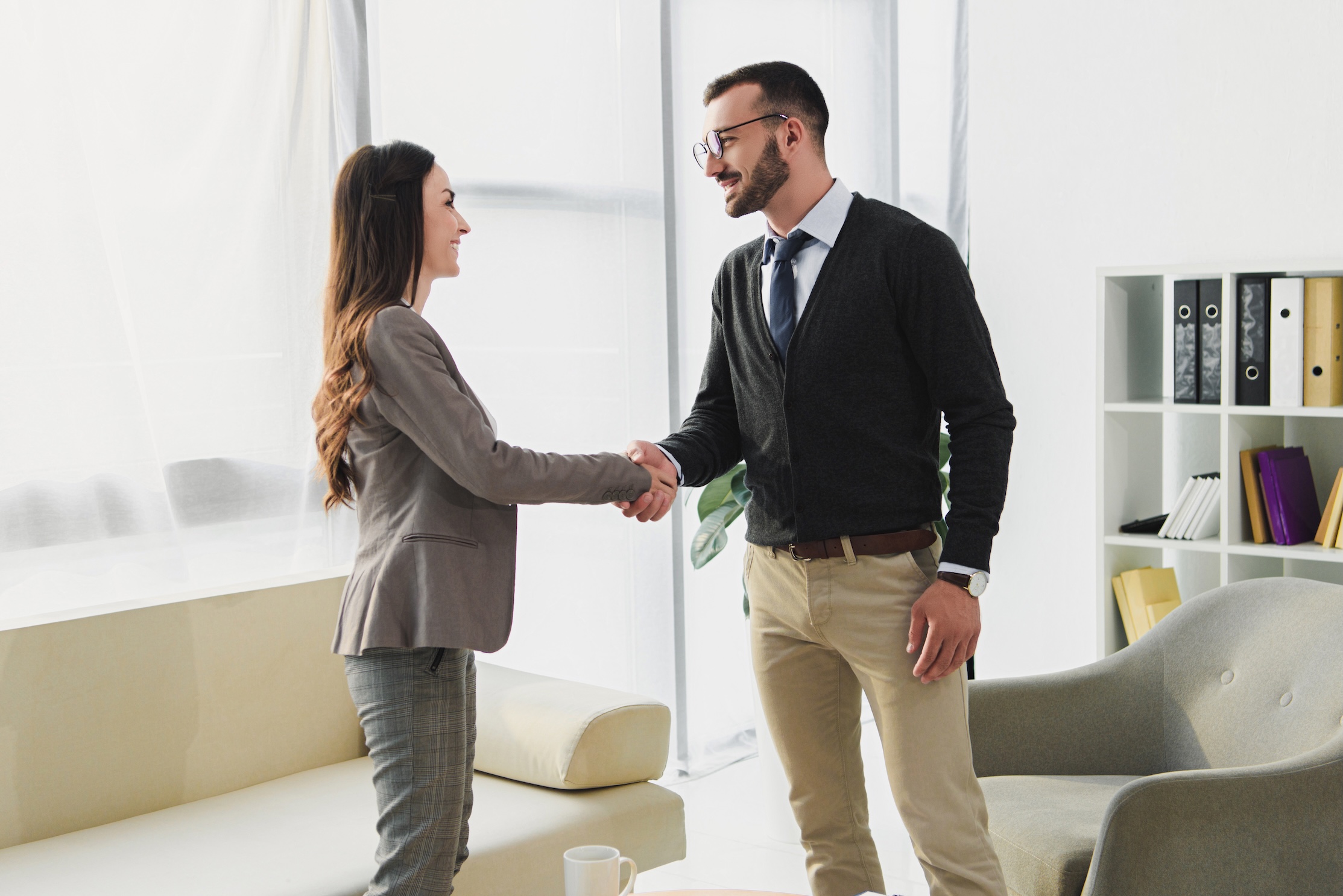 Man and woman shaking hands before reviewing insurance coverage