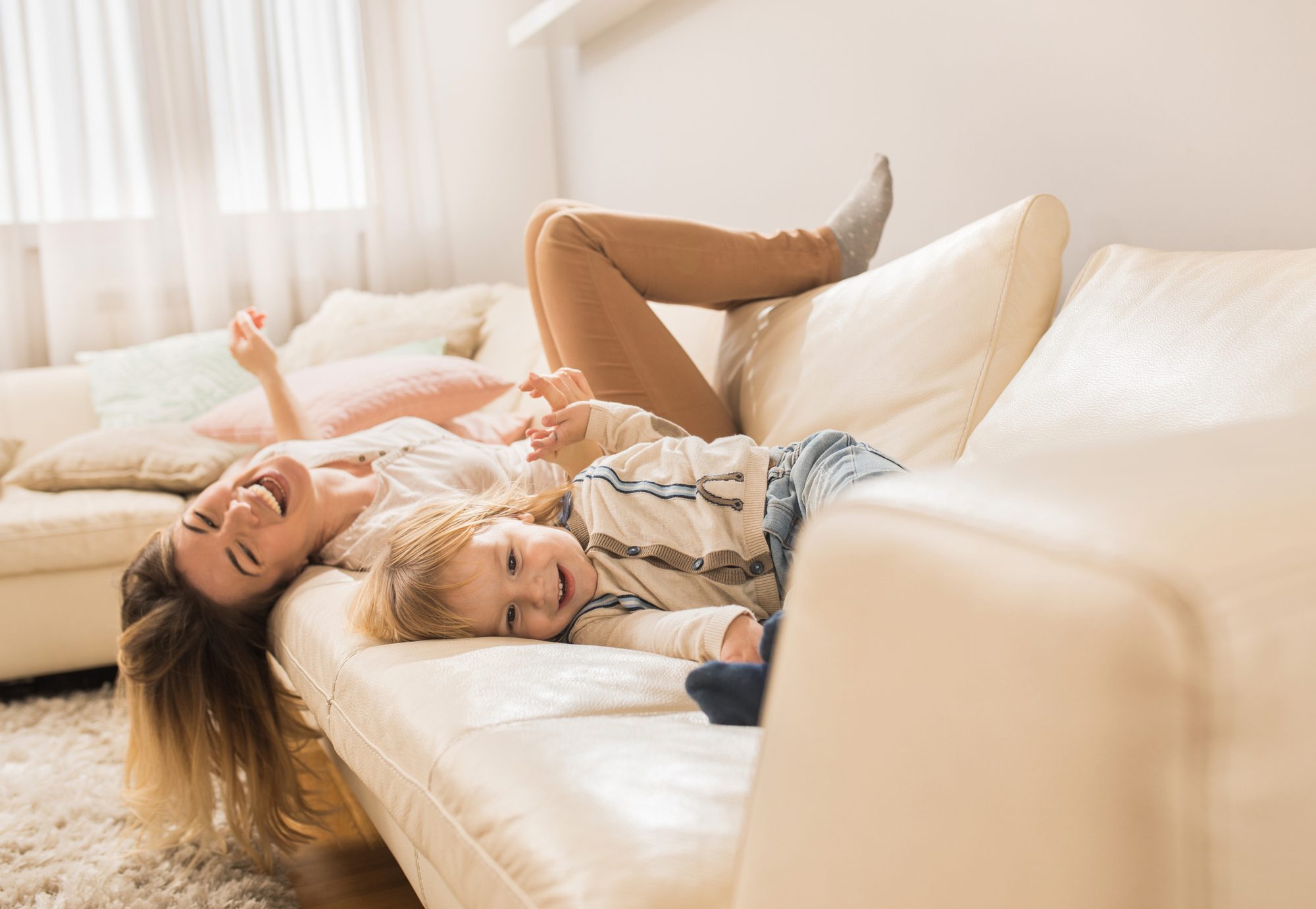 Mother and child laughing together on a living room sofa
