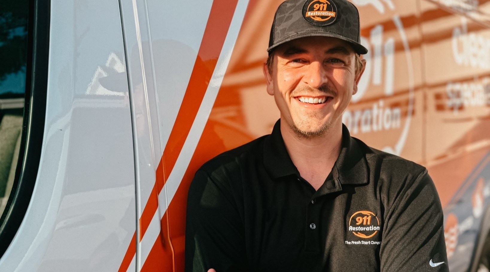 Nolan from 911 Restoration of Coastal Carolina Headshot with orange service truck behind him
